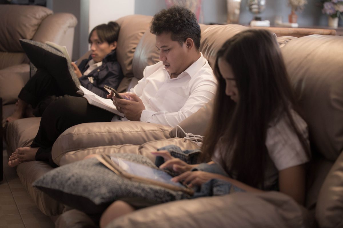 Tre personer i samme sofa, hver med sin egen mobil eller nettbrett.