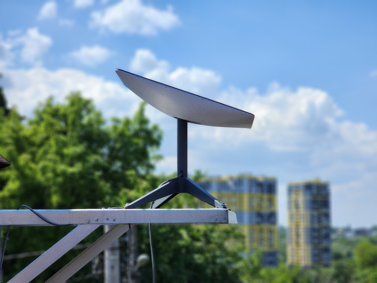 Flat satellittantenne på stativ montert utendørs med fri sikt mot himmelen.